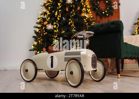 Ein Oldtimer-Rennwagen für Kleinkinder vor einem Weihnachtsbaum Stockfoto