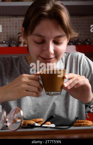 Eine junge Frau, die Ihren Kaffee mit Milch genießt Stockfoto