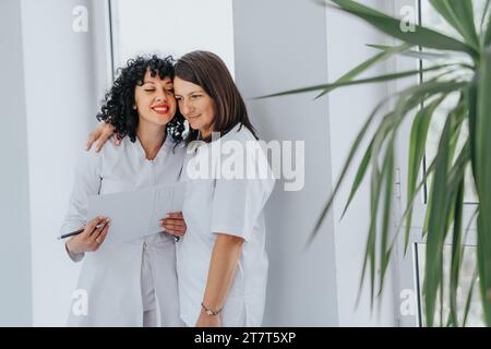 Glückliche erfolgreiche Ärztinnen, die sich gegenseitig umarmen, nachdem sie das Leben der Patienten gerettet haben. Kopierbereich. Stockfoto