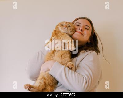 Die junge Frau umarmt ihre Scottish Fold Katze. Stockfoto