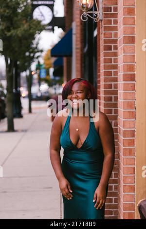 Lachende schwarze Teenagerin in formellem grünen Kleid in der Innenstadt Stockfoto