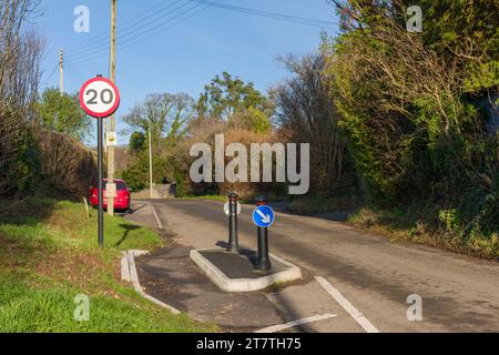 Ein Schild mit einer Geschwindigkeitsbegrenzung von 20 Meilen pro Stunde und Maßnahmen zur Verkehrsberuhigung auf einer Landstraße, wo es in das ländliche Dorf Wrington, North Somerset, England, eindringt. Stockfoto