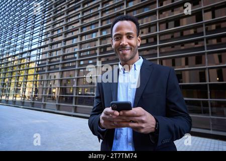 Portrait junger afroamerikanischer professioneller Mann, der mit mobiler Außenbeleuchtung in die Kamera lächelnd schaut. Stockfoto