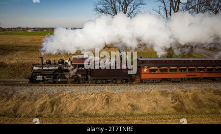 Ronks, Pennsylvania, 4. Dezember 2022 - Parallel View of a restaurierten Antique Steam Passenger Train, der auf einer sonnigen Aut durch die Landschaft fährt Stockfoto