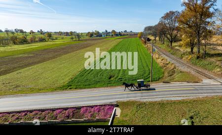 Ein Amish Pick Up Horse und Buggy aus der Vogelperspektive, die an einem sonnigen Herbsttag auf der Landstraße durch die Farm Fields fahren Stockfoto