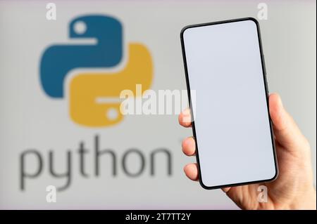 New York, USA – 15. November 2023: Erstellen einer neuen mobilen App auf Python-Plattform-Hintergrund mit einem sauberen Smartphone-Bildschirm in der Hand Stockfoto