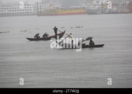 Dhaka, Wari, Bangladesch. November 2023. Bangladeschische Passagiere überqueren den Buriganga River während des starken Regens, da der Zyklon Midili das Küstengebiet in Dhaka, Bangladesch, am 17. November 2023 beeinflusst. Nach Angaben des Meteorologischen Departements Bangladesch (BMD) und der Bangladesch Inland Water Transport Authority (BIWTA) wird sich der Wirbelsturm Midili voraussichtlich weiter nordnordöstlich bewegen und die Küste bis 17. November Abend überqueren und alle Arten von Flussschiffen wurden aufgrund des Zyklonsturms ausgesetzt. aufgrund des Klimawandels treten in Bangladesch häufig Wirbelstürme und Überschwemmungen auf. (Guthaben Stockfoto