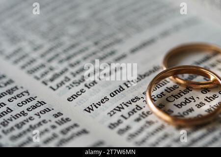 Zwei goldene Eheringe und geöffnete Seiten der heiligen Bibel repräsentieren das Konzept der Ehe und der Liebe zwischen zwei Christen Stockfoto