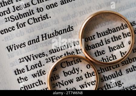 Zwei goldene Eheringe und geöffnete Seiten der heiligen Bibel repräsentieren das Konzept der Ehe und der Liebe zwischen zwei Christen Stockfoto