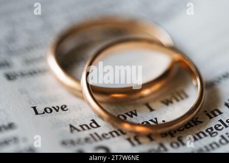 Zwei goldene Eheringe und geöffnete Seiten der heiligen Bibel repräsentieren das Konzept der Ehe und der Liebe zwischen zwei Christen Stockfoto