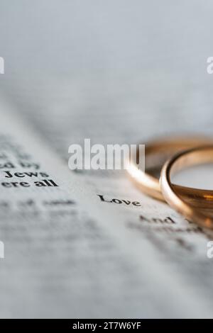 Zwei goldene Eheringe und geöffnete Seiten der heiligen Bibel repräsentieren das Konzept der Ehe und der Liebe zwischen zwei Christen Stockfoto