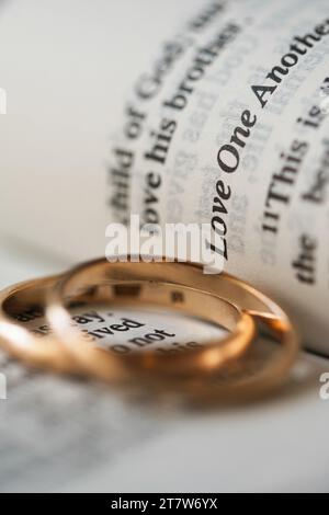 Zwei goldene Eheringe und geöffnete Seiten der heiligen Bibel repräsentieren das Konzept der Ehe und der Liebe zwischen zwei Christen Stockfoto