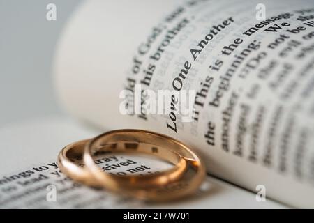 Zwei goldene Eheringe und geöffnete Seiten der heiligen Bibel repräsentieren das Konzept der Ehe und der Liebe zwischen zwei Christen Stockfoto