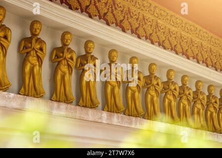 Reihe goldener Buddha-Statuen, jede in einer betenden Haltung, in einem alten thailändischen Tempel Stockfoto