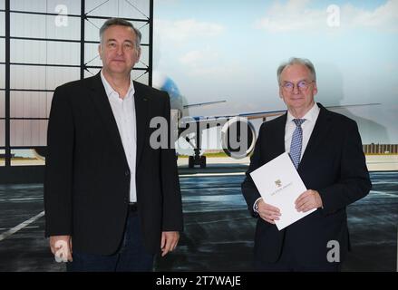 Schkeuditz, Deutschland. November 2023. Markus Otto (l), Geschäftsführer der DHL European Air Transport Leipzig GmbH, und reiner Haseloff (CDU), Ministerpräsident von Sachsen-Anhalt, stehen am Flughafen Leipzig/Halle vor einem Plakat eines Flugzeugs. Haseloff traf sich, um das Thema Fluglärm in Sachsen-Anhalt zu erörtern. Quelle: Sebastian Willnow/dpa/Alamy Live News Stockfoto