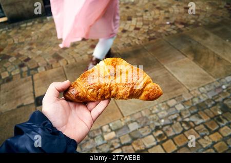 Die Hand hält ein klassisches französisches Croissant mit einer köstlichen goldenen Kruste Stockfoto