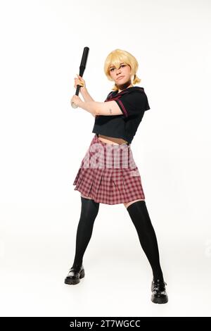 Volle Länge einer unzufriedenen Frau in Schuluniform mit Baseballschläger auf weißem Anime-Charakter Stockfoto