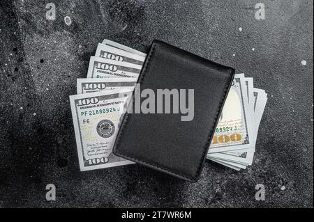 Eine schwarze Handtasche mit dem großen Päckchen Dollar, Bargeld-Schein. Schwarzer Hintergrund. Draufsicht. Speicherplatz kopieren. Stockfoto