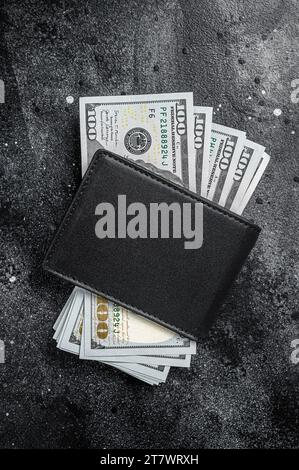 Eine schwarze Handtasche mit dem großen Päckchen Dollar, Bargeld-Schein. Schwarzer Hintergrund. Draufsicht. Speicherplatz kopieren. Stockfoto