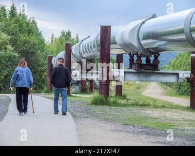 Mann und Frau, die neben der Alaska-Pipeline in der Nähe von Fairbanks, Alaska, laufen. Stockfoto