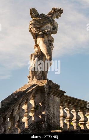 Eine Statue eines jungen Mannes von Orazio Marinali, stehend auf einer Steinbalustrade in den romantischen Gärten der Villa Trissino Marzotto aus dem 18. Jahrhundert, Vicenza, Italien Stockfoto