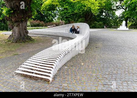 Einheimische entspannen auf einer interessanten weißen modernen Bank in einem der Parks im Zentrum von Tallinn, Estland Stockfoto