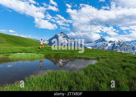 Glücklicher Wanderer, der sich im Wasser eines kleinen Sees unter dem Berner Oberland spiegelt, Bachalpsee, Grindelwald, Kanton Bern, Schweiz, Europa Stockfoto