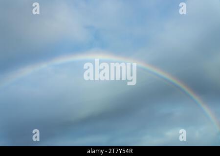 Echtes Foto eines Regenbogens am Himmel mit Wolken und blauem Himmel Stockfoto