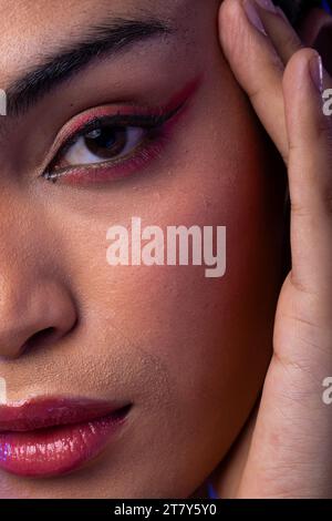 Eine Frau mit dunklem Haar, Hand-zu-Gesicht, roten Lippen, Lidschatten-Make-up Stockfoto