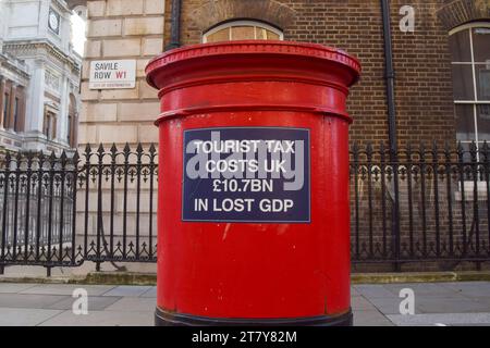 London, Großbritannien. November 2023. Ein Schild, das unbekannte Aktivisten an einem Briefkasten in der Saville Row im Londoner West End klebten, lautet: "Die Tourismussteuer kostet Großbritannien 10,7 Milliarden Pfund an verlorenem BIP". Quelle: Vuk Valcic/Alamy Live News Stockfoto