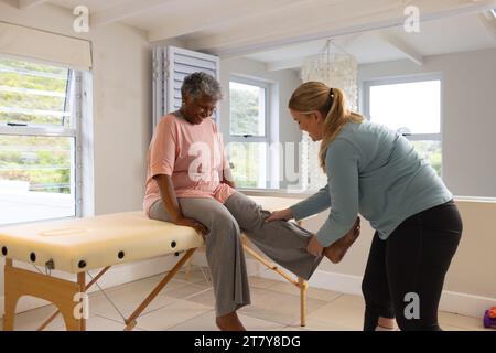 Kaukasische Physiotherapeutin behandelt ältere afrzianische amerikanische Patientin, Kopierraum Stockfoto