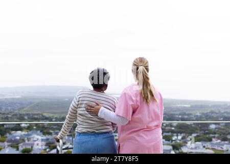 Kaukasische Krankenschwester und ältere afroamerikanische Patientin auf Balkon Stockfoto