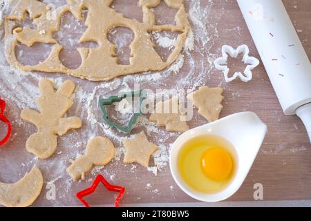 Layout der Ausstecher Close-up schneidet Kekse aus dem Teig mit Formen über ein Weihnachtsmotiv in Form eines Schneemanns, eines Weihnachtsbaums, Sterne in Stockfoto