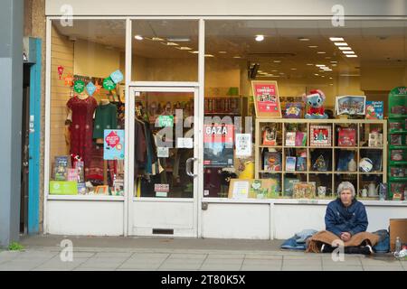 Uxbridge, Großbritannien. November 2023. Ein Obdachloser sitzt vor einem Oxfam Charity Shop im Stadtzentrum von Uxbridge im Londoner Stadtteil Hillingdon. Die Pläne der ehemaligen Innenministerin Suella Braverman, keine Wohltätigkeitsorganisationen mehr an Obdachlose zu vergeben, wurden von der Regierung aufgegeben. Quelle: Maureen McLean/Alamy Live News Stockfoto