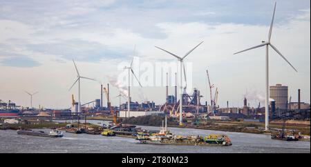 Windturbinen an einem Industriehafen mit verankerten Lastkähnen, Produktionsstätten, an der Amstel, die nach Amsterdam führt Stockfoto