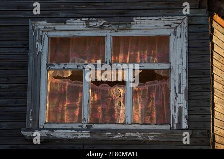 Ein Fenster im Holzhaus, das von der Sonne beleuchtet wird, durch das Fenster auf der anderen Seite des Hauses, Region Archangelsk, Russland Stockfoto
