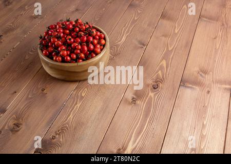 Rote Hagebuttenfrüchte in einer Holzschale auf Holztisch Stockfoto