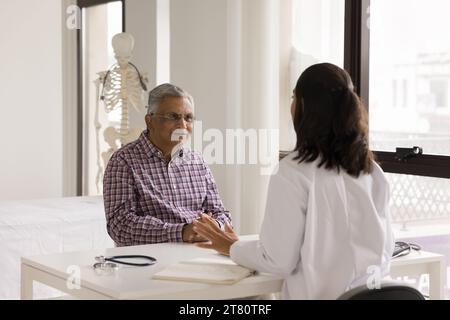 Positiver Senior-indischer Patient-Mann, der junge Ärztin berät Stockfoto