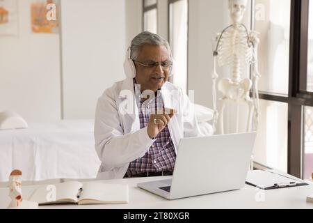 Positiver reifer indischer Doktor, der auf Videoanruf spricht Stockfoto