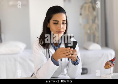 Ernsthafte junge lateinische Kardiologin, die Patienten überprüft Stockfoto