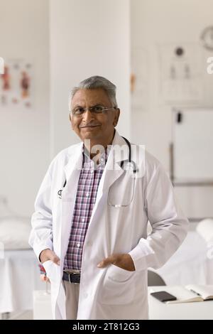 Positiver glücklicher leitender indischer Arzt, der im Klinikbüro steht Stockfoto