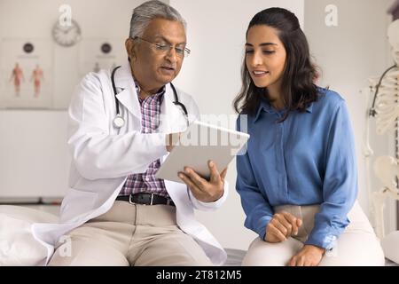Konzentrierte, verschiedene leitende Ärzte und junge Patienten mit Blick auf das Tablet Stockfoto