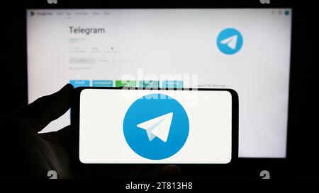 Person, die ein Smartphone mit dem Logo des Instant Messaging-Dienstes Telegram Messenger vor der Website hält. Schwerpunkt auf dem Display des Telefons. Stockfoto