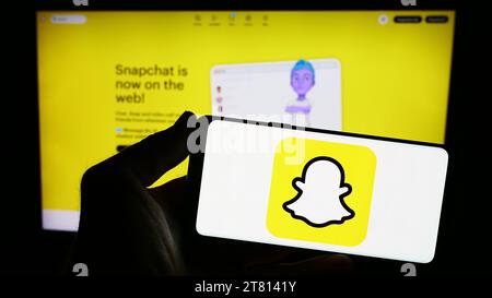 Person, die ein Smartphone mit dem Logo der US-Multimedia-Instant-Messaging-App Snapchat vor der Website hält. Schwerpunkt auf dem Display des Telefons. Stockfoto
