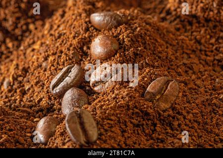 Kaffeemusik. Kaffeebohnen liegen auf einem Haufen gemahlenen Kaffees, Nahaufnahme, Frontalansicht. Stockfoto