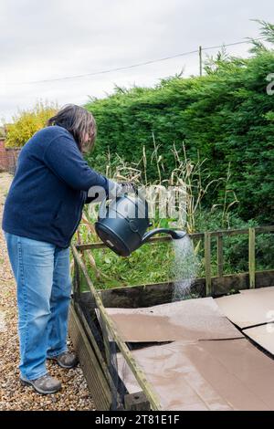 Keine Gartenarbeit. Boden, der mit Pappe bedeckt ist, um Unkraut zu unterdrücken, bewässert, Gartenkompost auf der Oberseite verteilt und über den Winter zurückgelassen wird. Stockfoto