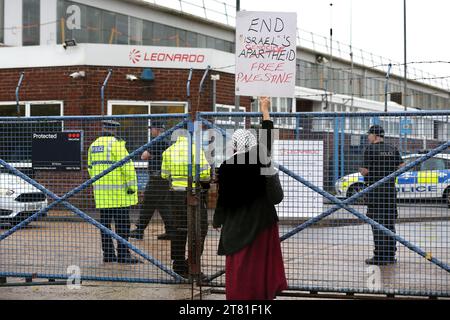 Southampton, Hampshire, Großbritannien. November 2023. Ein Unterstützer der palästinensischen Sache hält ein Plakat an den Fabriktoren. Palästina-Aktion besetzt das Dach der italienischen Rüstungsindustrie, der Riese Leonardo in seiner Fabrik in Southampton. Leonardo beliefert Israel mit Kampfjets und Waffen, die derzeit im Gazastreifen eingesetzt werden. Palestine Action verlangt, dass Waffenunternehmen, die Waffen für Israel bereitstellen, dauerhaft geschlossen werden. Sie haben angekündigt, dass Unternehmen, die Waffen an die israelischen Streitkräfte verkaufen, und ihre Partnerunternehmen mit direkten Maßnahmen ins Visier genommen werden. Diese Aktionen Stockfoto