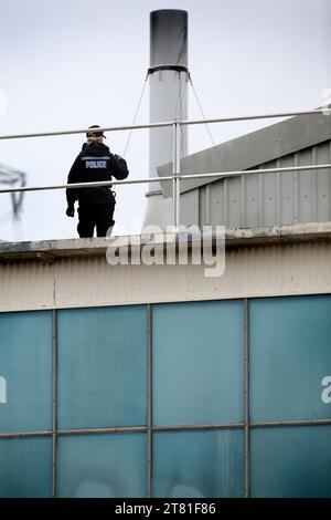 Southampton, Hampshire, Großbritannien. November 2023. Ein Polizist steht auf dem Dach bereit, als Rettungsdienste das Dach von Demonstranten räumen. Palästina-Aktion besetzt das Dach der italienischen Rüstungsindustrie, der Riese Leonardo in seiner Fabrik in Southampton. Leonardo beliefert Israel mit Kampfjets und Waffen, die derzeit im Gazastreifen eingesetzt werden. Palestine Action verlangt, dass Waffenunternehmen, die Waffen für Israel bereitstellen, dauerhaft geschlossen werden. Sie haben angekündigt, dass Unternehmen, die Waffen an die israelischen Streitkräfte verkaufen, und ihre Partnerunternehmen mit direkten Maßnahmen ins Visier genommen werden Stockfoto