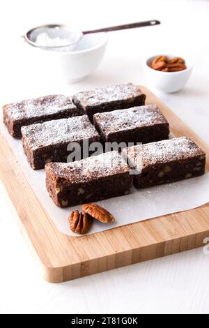 Hausgemachte Schokoladen-Brownies mit Schokolade und Pekannüssen, bestäubt mit Puderzucker. Stockfoto