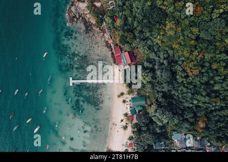 Blick von oben oder aus der Vogelperspektive auf das Fischerdorf mit weißem Strand und Booten im Sommer auf die tropische Insel Perhentian Kecil Stockfoto